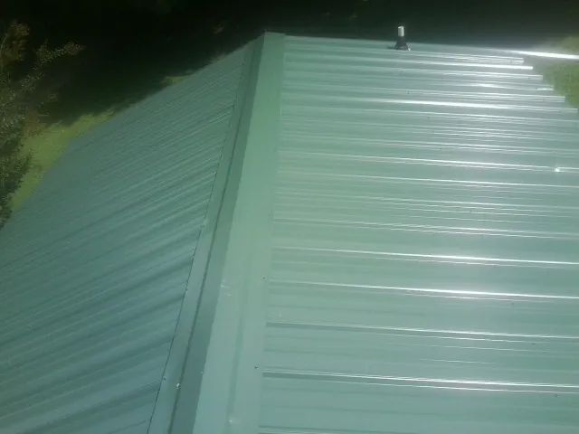 New green metal panels meeting at the ridge of a roof — Flat Roof Repair work by our crew in Honey Creek