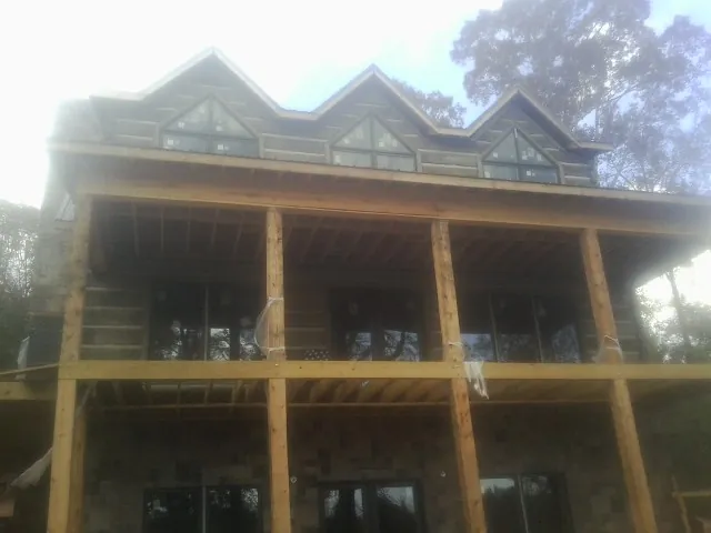 Dormers and porch framing on a large log home under construction — Roof Coating work by our crew in Honey Creek