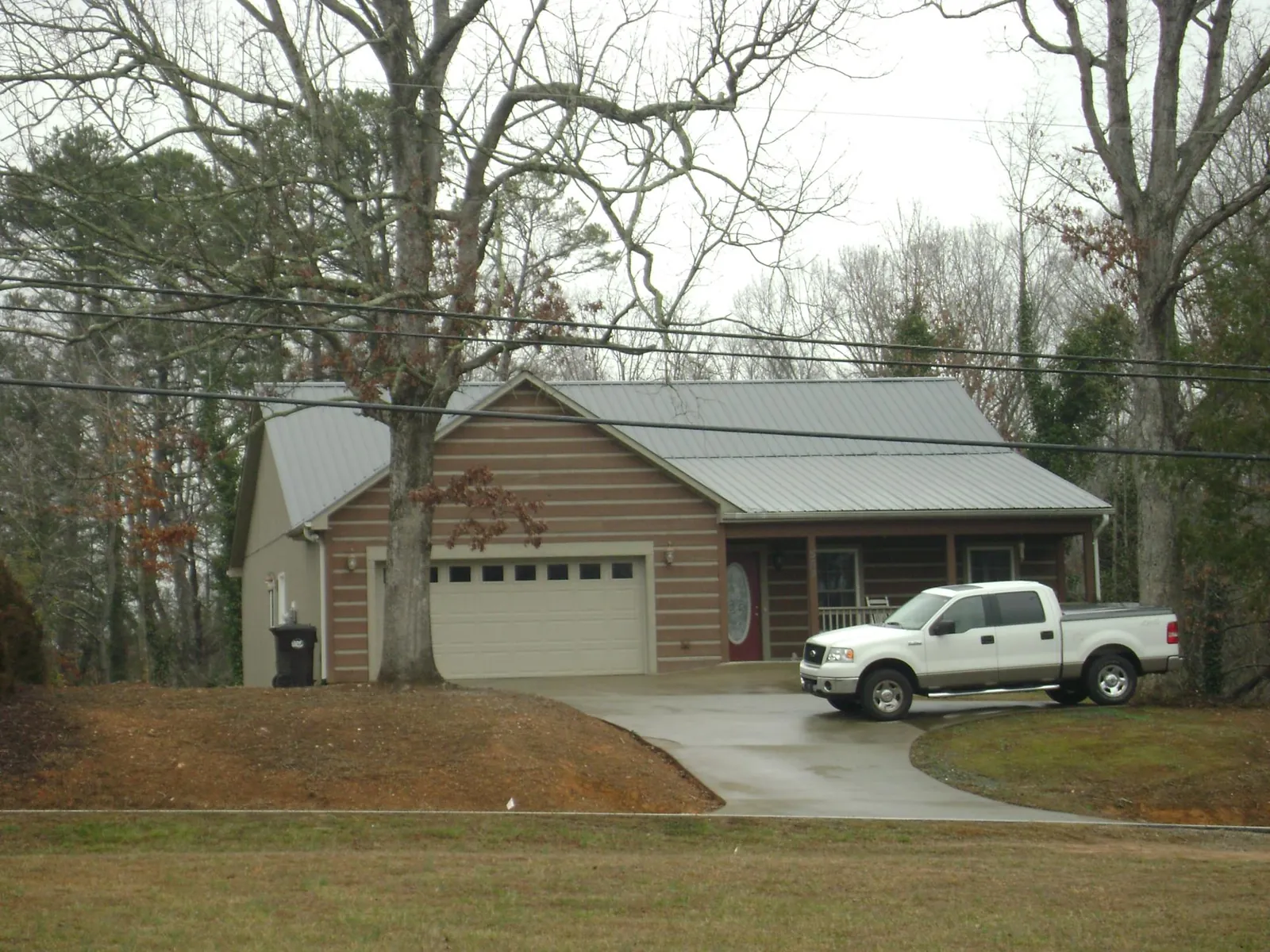 Gray metal roof on a log sided house with an attached two car garage in Honey Creek