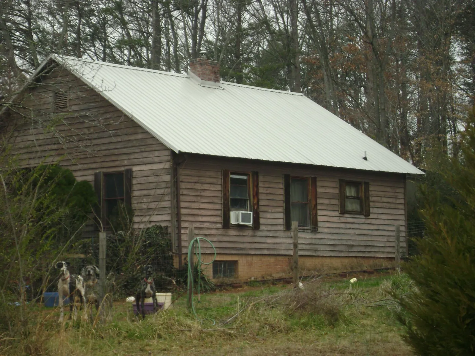 White metal roof on an old wood sided farmhouse, from a Metal Roof Installation job in Honey Creek