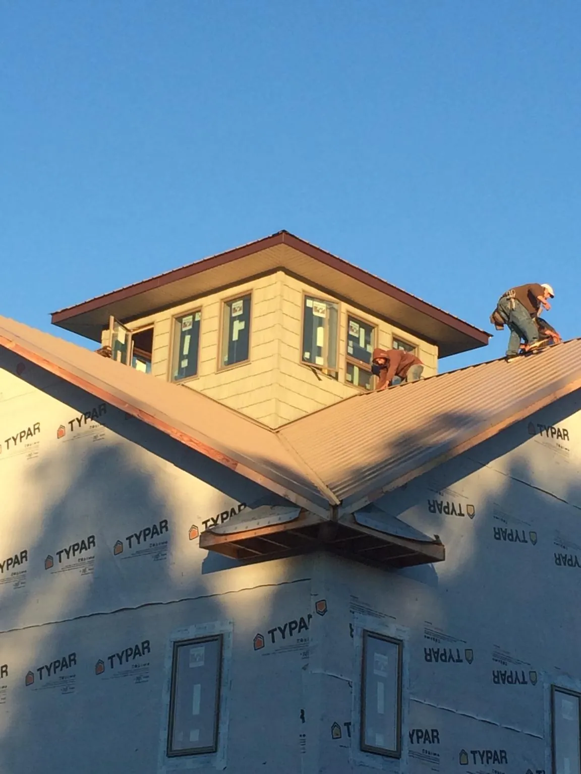 Roofers working around a rooftop cupola on a new metal roof at sunset — Roof Waterproofing in Honey Creek by Roofing Brothers